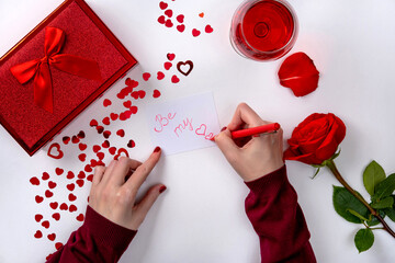 Woman writing love letter for Valentines day. Female hands write writing love letter at the desk, top view
