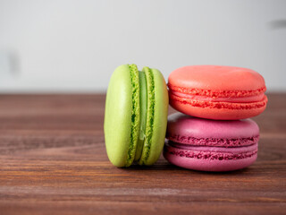 three macaroons on a wooden background. The back has a light blurred background. Side view. Delicious sweet dessert