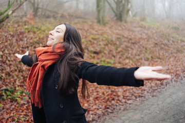 Beautiful woman enjoying freedom with stretched arms in Autumn