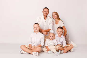 happy parents and three beautiful children embrace on a white background