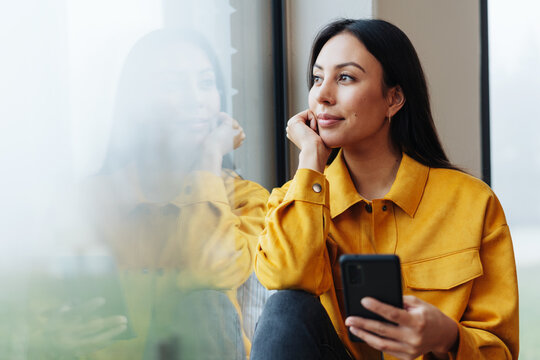Relaxed woman sitting daydreaming on a window seat