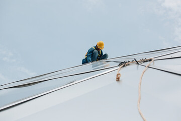 Male workers rope access height safety connecting with a knot safety harness, to ascending, construction site oil tank dome.