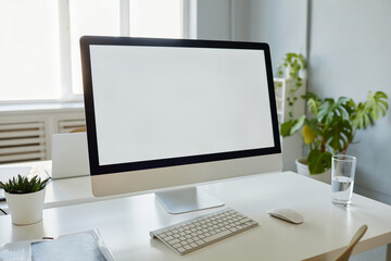 Minimal background image of office workplace with blank white computer screen on desk, copy space