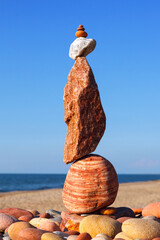 Rock zen pyramid of stones of different shapes on a background of blue sky and sea.