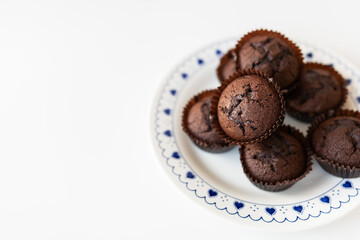 Chocolate muffins lie on a white plate with small hearts. Close-up, space for an inscription.