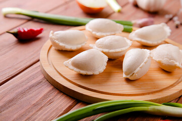 Fototapeta na wymiar Raw dumplings with cabbage on a wooden background