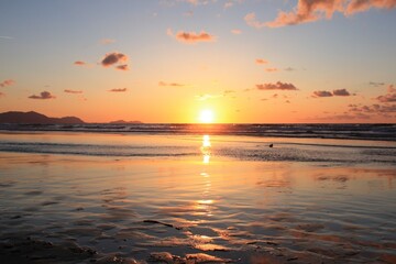 Playa de Sopelana al anochecer con el horizonte con el sol al centro a punto de esconderse con el agua a nuestros pies
