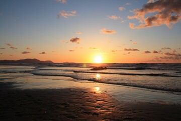 Fototapeta na wymiar Playa de Sopelana al anochecer con el horizonte con el sol al centro a punto de esconderse