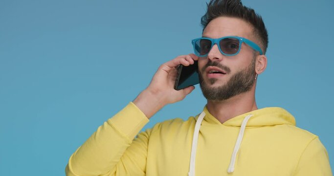 attractive casual man wearing blue sunglasses, talking on the phone, slapping his head and gesturing never mind