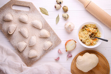 Raw dumplings with cabbage on white wooden background. Vareniki is a dish of Slavic cuisine. Top view.