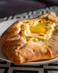 Adjarian khachapuri with fresh egg on table, Caucasian Georgian cuisine