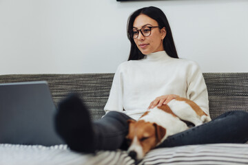 Woman working from home with her dog on a sofa