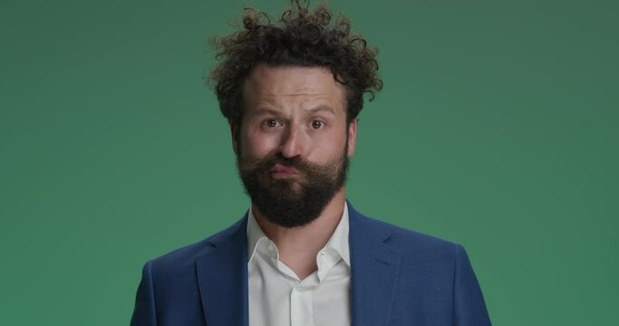 green background presenting crazy businessman with beard and moustache making funny faces, being idiot, grimacing in studio