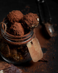 Chocolate truffle. Dark chocolate sprinkled with cocoa on a dark rustic wooden background. Atmospheric food photo. Homemade fresh energy balls.