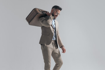 side view of attractive man with suitcase over shoulder looking down