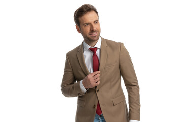 young businessman arranging his tie and looking to the side