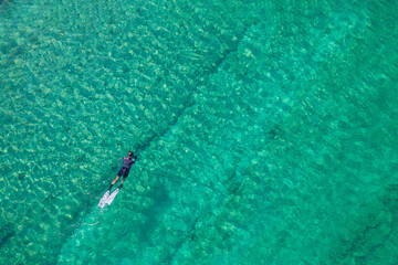 Spearfishing scuba diver in tropical exotic sea, ocean turquoise clear water. Man swimming hunting exotic fish, poaching. Top view. Aerial, drone, copter view.