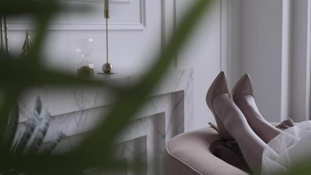 female legs dangle on the corner of the sofa