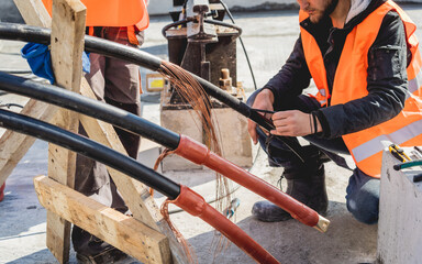 Two electrician builder workers installing high-voltage cable
