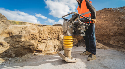 Worker uses a portable vibration rammer at construction of a power transmission substation