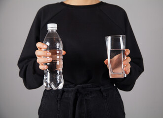 Woman holding a bottle with a glass of water.