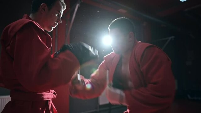 Taekwondo practitioner in a red kimono is training in a gym. Slow motion
