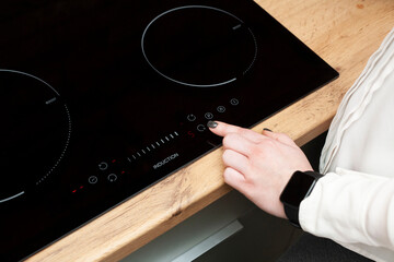 A woman's hand turns on an induction furnace. Cooking. Touch panel induction furnace.