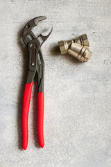 Adjustable pliers on gray concrete background close-up top view