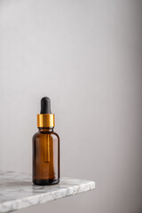 Fototapeta premium Minimalistic composition with a glass brown bottle of serum with a pipette for skin care. The concept of health and beauty. copy space