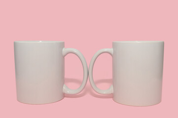 Two white mugs on a pink background. Layout for design. Close-up.