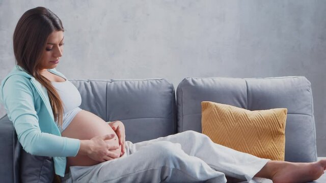 Young pregnant woman is resting at home and expecting a baby. The concept of pregnancy, motherhood, health and lifestyle.
