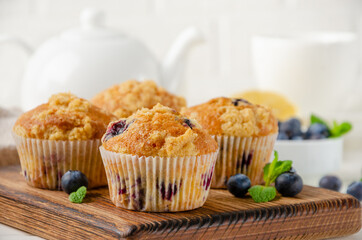 Lemon muffins with blueberries and shtreisel with fresh berries on a white wooden background. Delicious breakfast. Copy space.