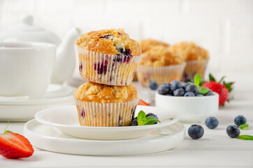 Lemon muffins with blueberries and shtreisel with fresh berries on a white wooden background....