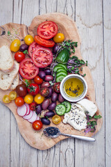 healthy snack of olives, tomatoes, olive oil, bread and cucumber