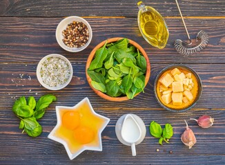 Prepared ingredients for cooking fritata or omelet on a dark wooden background. Spinach recipes.