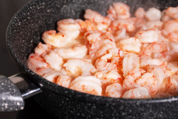Prawns cooking. Frying pan with fried peeled shrimps spices and smoke, close up. Mediterranean, keto diet. Healthy food