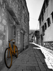 Yellow bicycle in a black and white street in Stari Grad in Hvar island Croatia