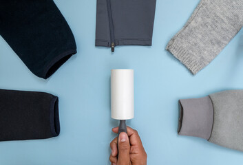 Close up photo of sticky lint roller or hair remover and clothes produced of different kinds of...