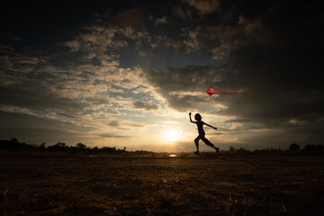 Silhouette of children flying a kite on sunset