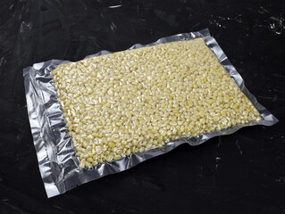 Vacuum packed pine nuts without shells on a black background. Pine nuts in a package close up. Nuts...