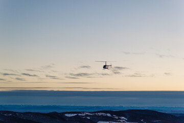 View of the slope of the ski resort at sunset with a riding snowmobile