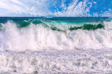 Beautiful big waves of the sea in the summer bright blue, turquoise colors in the early morning in sunlight on a blue sky.