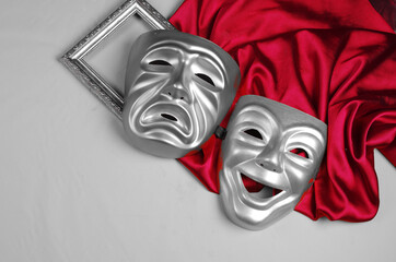 Art attributes.Theater.Theatrical masks of tragedy and comedy, frame and burgundy drapery on a gray...