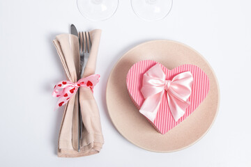 Top view heart-shape gift box on plate and cutlery  on the table. Serving and gift for a romantic dinner on valentine's day concept