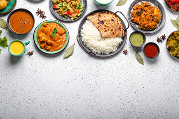 Indian ethnic food buffet on white concrete table top view: curry, samosa, rice biryani, dal, paneer, chapatti, naan, chicken tikka masala, mango lassi, dishes of India dinner background copy space - 480757617