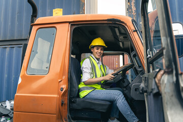 Naklejka premium Asian woman truck driver sitting in truck cabin looking at camera.