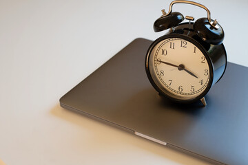 Close-up of alarm clock standing on laptop. Concept of work hours, deadline and limit screen time. 