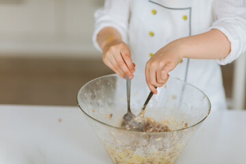 two children's hands stir dough in a bowl. child bakes something 