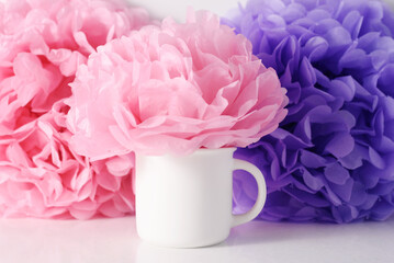 Obraz premium Romance mockup of white mug on a pink and lilac paper flowers background for Valentine's day, wedding or Mothers day, template for your design.