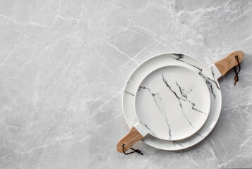 Banner. An empty ceramic marble plate with a wooden handle on the background of a gray concrete table. Space for text. Menu concept for cafes and restaurants.